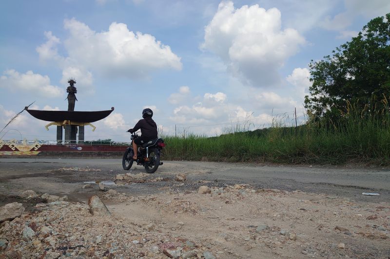 Warga berkendaraan roda dua sedang melewati jalan rusak di Jalan Terusan Endro Suratmin, yang merupakan salah satu akses utama menuju Desa Sabah Balau, Kabupaten Lampung Selatan, Lampung, Selasa